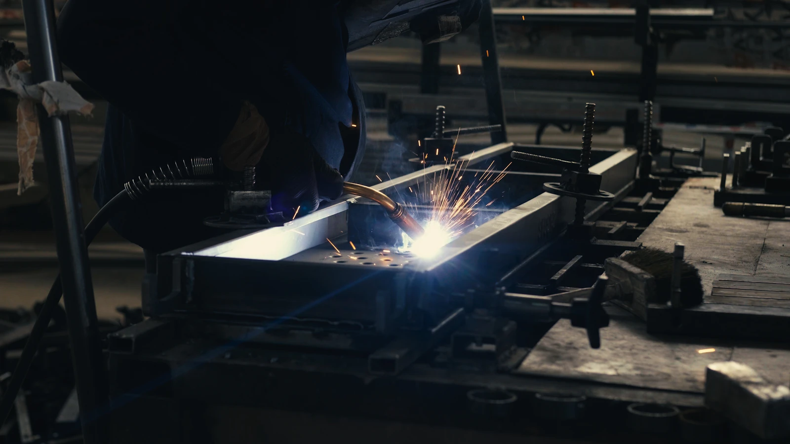 MIG welding a steel fabrication assembled from laser-cut parts on a jig table